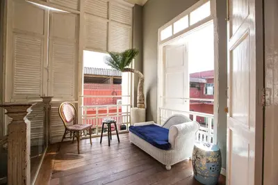 a balcony with a couch and chairs and a window at Azure Hostel Bangkok in Bangkok