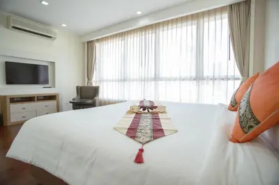 a hotel room with a white bed and a television at GM Serviced Apartment in Bangkok