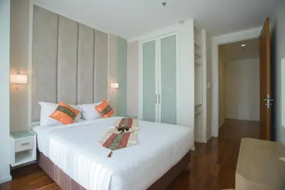 a bedroom with a large white bed with orange pillows at GM Serviced Apartment in Bangkok