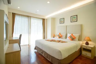a bedroom with a large white bed and a window at GM Serviced Apartment in Bangkok