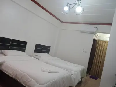 two beds in a bedroom with two lights on the ceiling at Hotel Paraiso in Bangkok