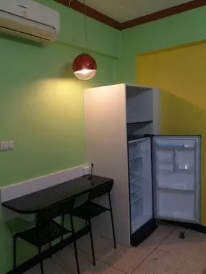 a kitchen with a refrigerator and a table and a counter at Hotel Paraiso in Bangkok