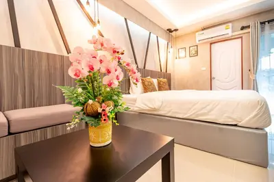 a room with a bed and a table with flowers at Tree Place in Bangkok