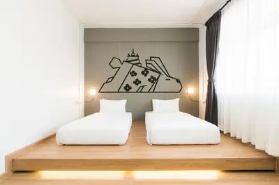 two beds in a room with a wall with a drawing on it at Marwin Villa in Bangkok