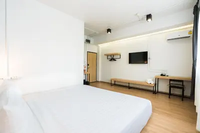 a bedroom with a white bed and a flat screen tv at Marwin Villa in Bangkok