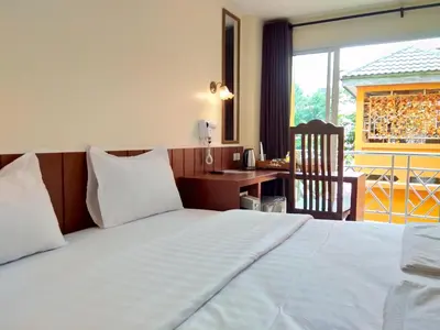 a bedroom with a bed and a desk and a window at Baan Wanchart in Bangkok