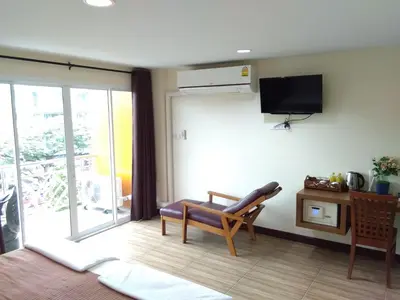 a living room with a chair and a sliding glass door at Baan Wanchart in Bangkok