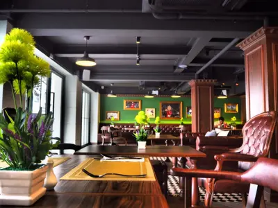 a restaurant with a table and chairs and green walls at Villa De Khaosan by Chillax in Bangkok