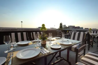a table with plates and wine glasses on a balcony at Villa De Khaosan by Chillax in Bangkok
