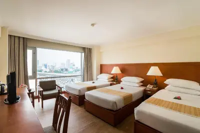 a hotel room with two beds and a large window at Bangkok Palace Hotel in Bangkok
