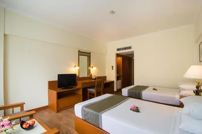 a hotel room with two beds and a desk at Bangkok Palace Hotel in Bangkok