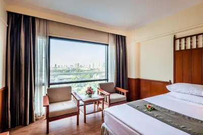 a hotel room with a bed and a large window at Bangkok Palace Hotel in Bangkok