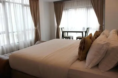a bedroom with a large white bed with windows at V One Pride-Sukhumvit 22, Bangkok in Bangkok