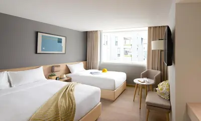 a hotel room with two beds and a window at Kritthai Residence in Bangkok