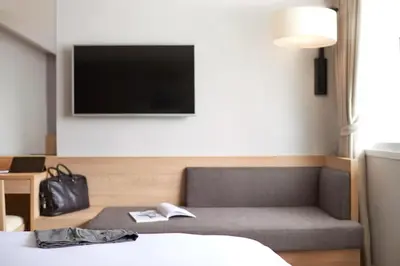 a hotel room with a bed and a chair and a tv at Kritthai Residence in Bangkok