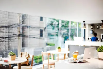 a restaurant with tables and chairs and a large window at Kritthai Residence in Bangkok