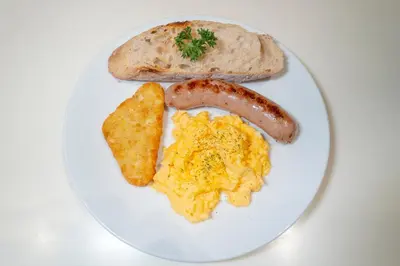 a plate of breakfast food with eggs sausage and toast at Kritthai Residence in Bangkok