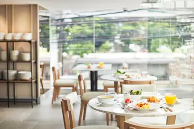 a restaurant with tables and chairs with food on them at Kritthai Residence in Bangkok