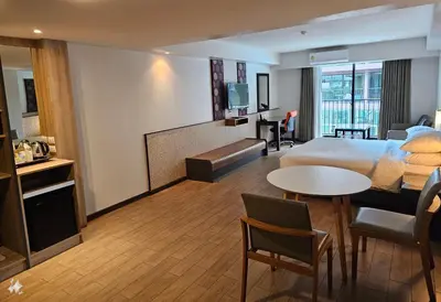 a hotel room with a bed and a living room at Dynasty Grande Hotel in Bangkok