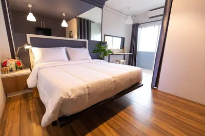 a bedroom with a large bed with a wooden floor at Mango 10 House in Bangkok
