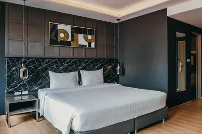 a bedroom with a large bed with a black wall at De Prime Rangnam Hotel in Bangkok