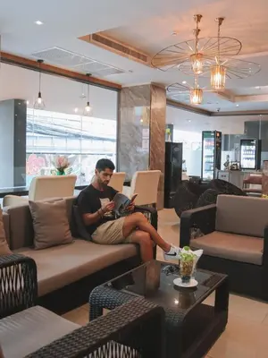 a man sitting on a couch in a living room at De Prime Rangnam Hotel in Bangkok