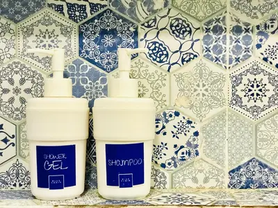 two bottles ofodorizers sitting on a shelf in front of a tile wall at Blu Cabin Ari Stylish Gay Poshtel in Bangkok