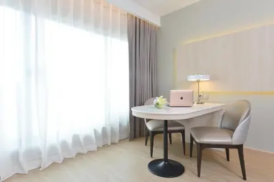 a room with a table and chairs with a laptop on it at Centre Point Plus Hotel Pratunam in Bangkok