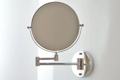 a round mirror on a white wall with a sink at Centre Point Plus Hotel Pratunam in Bangkok