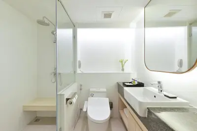 a bathroom with a toilet and a sink and a mirror at Centre Point Plus Hotel Pratunam in Bangkok