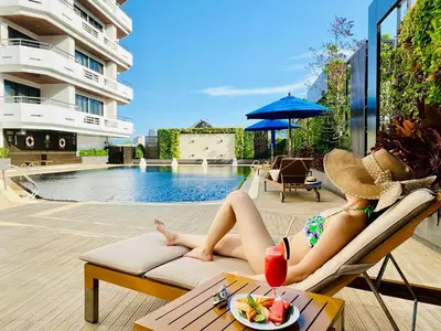 a woman laying on a couch next to a swimming pool at Centre Point Sukhumvit 10 in Bangkok