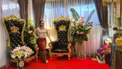 a woman is standing between two throne chairs at SUDYOD HOTEL in Ban Bang Bamru