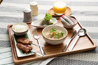 a tray of food with rice and meat and a glass of orange juice at Sukhon Hotel - SHA Plus in Bangkok