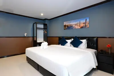 a bedroom with a large white bed with blue walls at The Breton Hotel Media in Bangkok