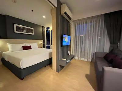 a bedroom with a bed and a tv and a couch at Arize Hotel Sukhumvit in Bangkok