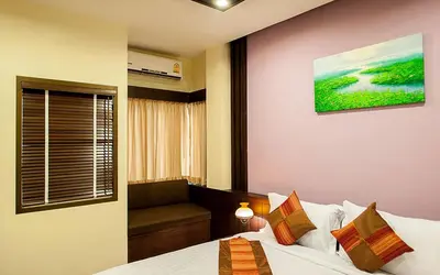 a hotel room with a bed and a window at Tara Place Hotel Bangkok in Bangkok
