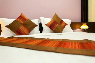 a bed with four pillows at Tara Place Hotel Bangkok in Bangkok