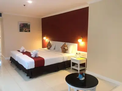 a hotel room with a large bed and a table at Bay Hotel Srinakarin in Bangna