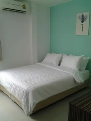 a bed with white sheets and pillows in a room at Nantra Ekkamai Hotel in Bangkok