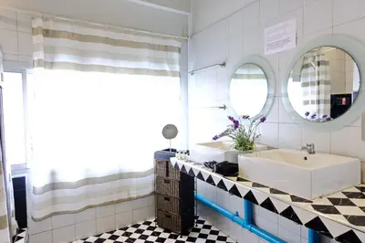 a bathroom with a tub and a sink and mirrors at Bangkok Nomad Hostel in Bangkok