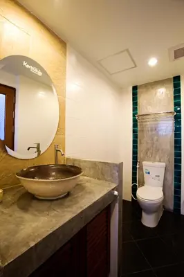 a bathroom with a sink and a toilet and a mirror at Korbua House in Bangkok