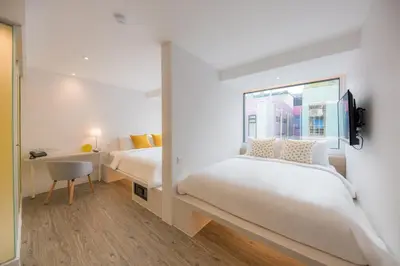 a bedroom with two beds and a window at Yello Rooms Hotel Victory Monument in Bangkok