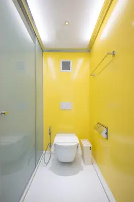 a bathroom with a toilet and a yellow wall at Yello Rooms Hotel Victory Monument in Bangkok