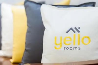 a white pillow with the ubico logo on it at Yello Rooms Hotel Victory Monument in Bangkok