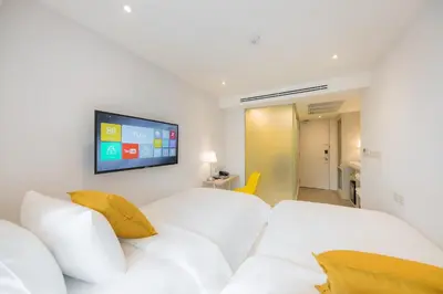 a hotel room with two white beds and a flat screen tv at Yello Rooms Hotel Victory Monument in Bangkok