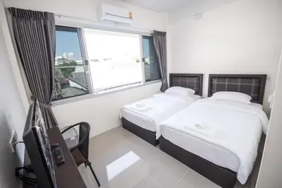 two beds in a small room with a window at ninaguesthouse in Bangkok