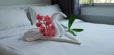 a white swan towel with pink flowers on a bed at NK Guesthouse 2 in Bangkok