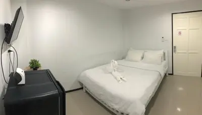 a white bedroom with a bed with a towel on it at NK Guesthouse 2 in Bangkok