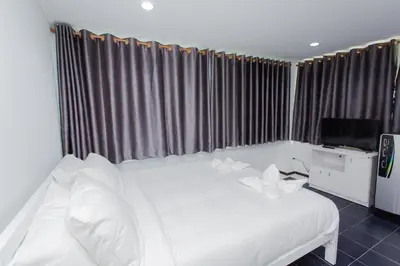 a bedroom with a white bed and a television at NK Guesthouse 2 in Bangkok