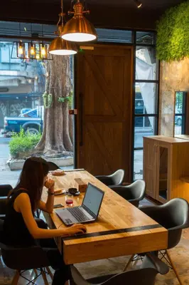 a woman sitting at a table with a laptop at Comfy Bed Hostel in Bangkok